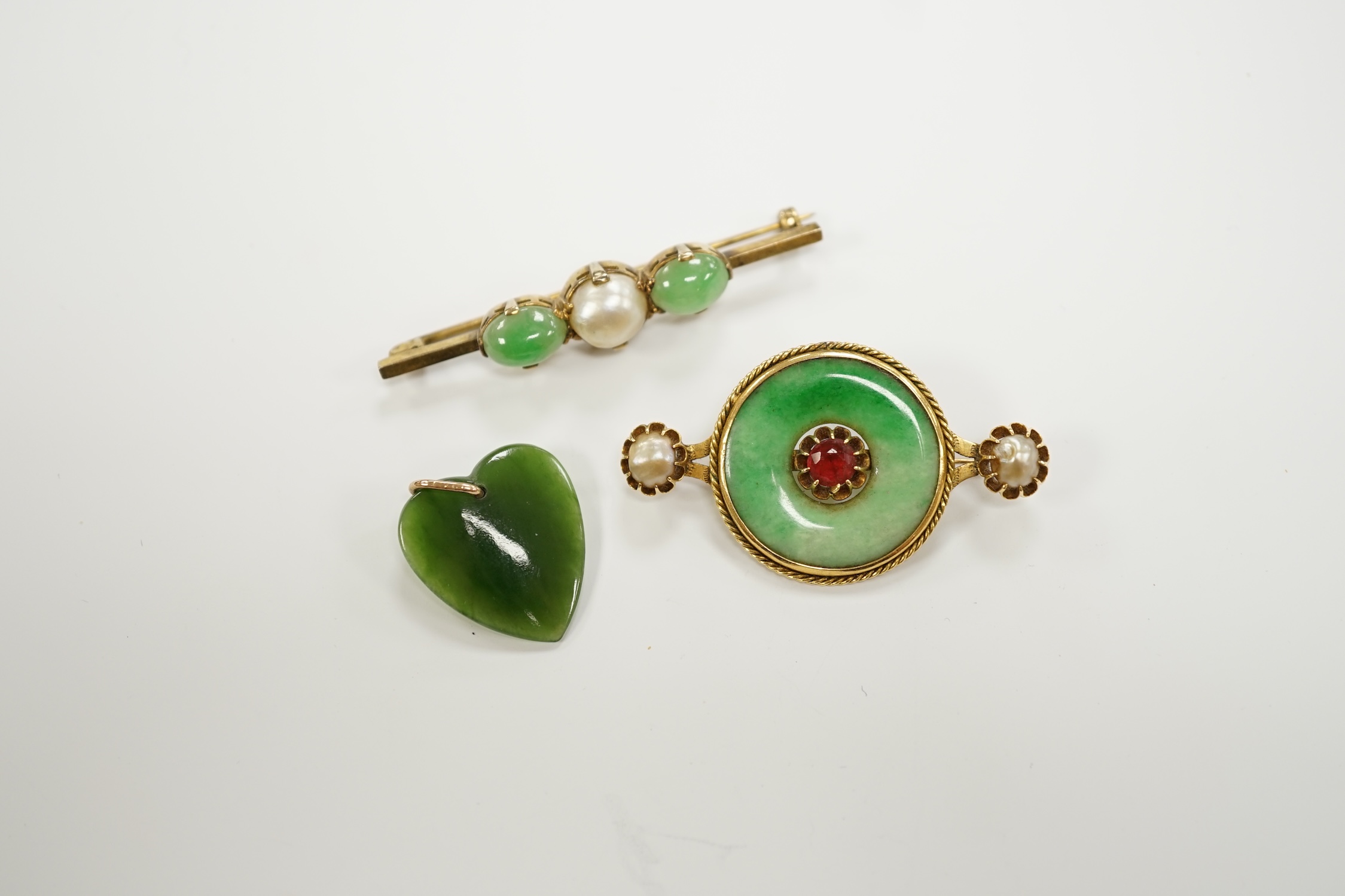 A Chinese 18k mounted, jade, cultured pearl and gem set disc brooch, 48mm, together with a yellow metal, jade and cultured pearl set bar brooch and a nephrite pendant.